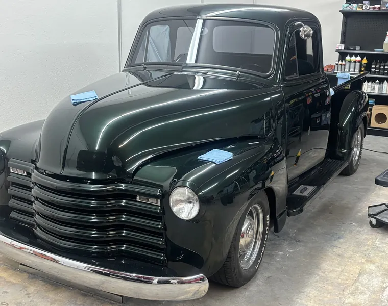Dark green Chevrolet 3100 pickup being detailed in the shop